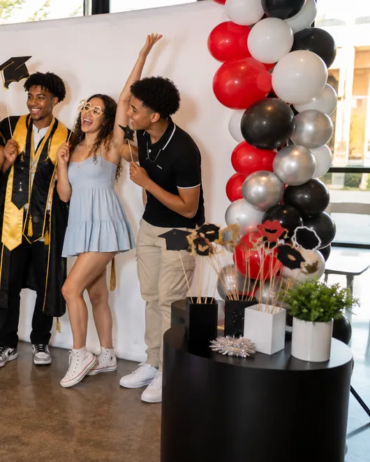 Graduates posing at the booth in front of a plain solid-color backdrop.