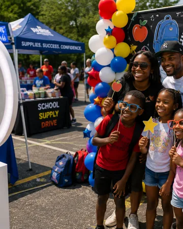 Families with star props at an outdoor community event, tents and balloons behind them.